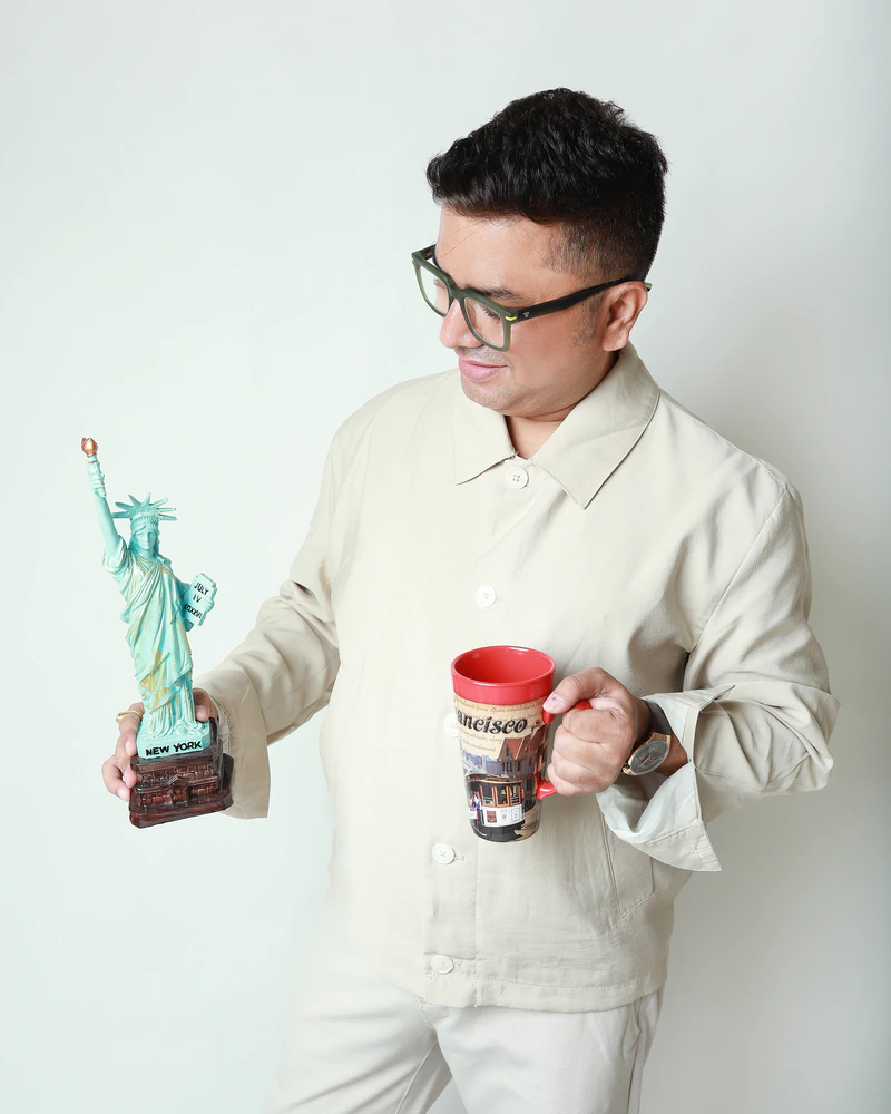 Vipul Joshi holding a Statue of Liberty souvenir and a mug